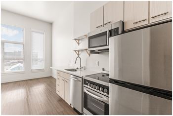 A kitchen with a stainless steel refrigerator, oven, and sink.